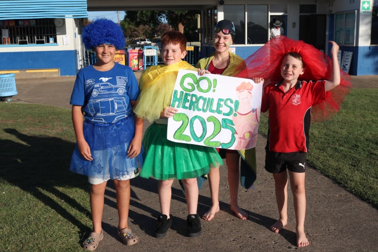 Four students dressed in house colours holding a sign